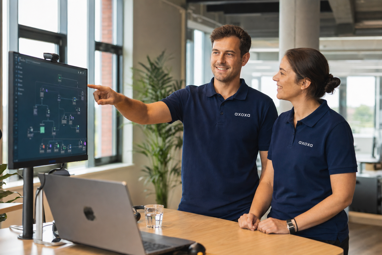 Orbito-medewerkers in bedrijfskleding bespreken een AI-workflow aan een groot scherm in een modern kantoor.